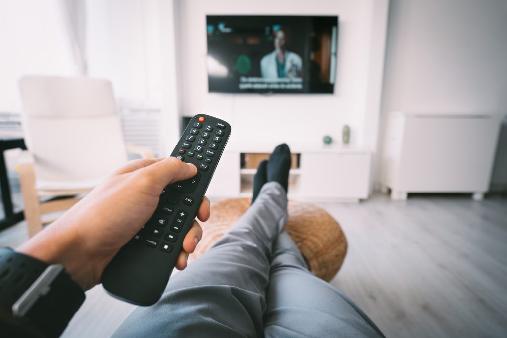 Man holding TV remote and watching TV